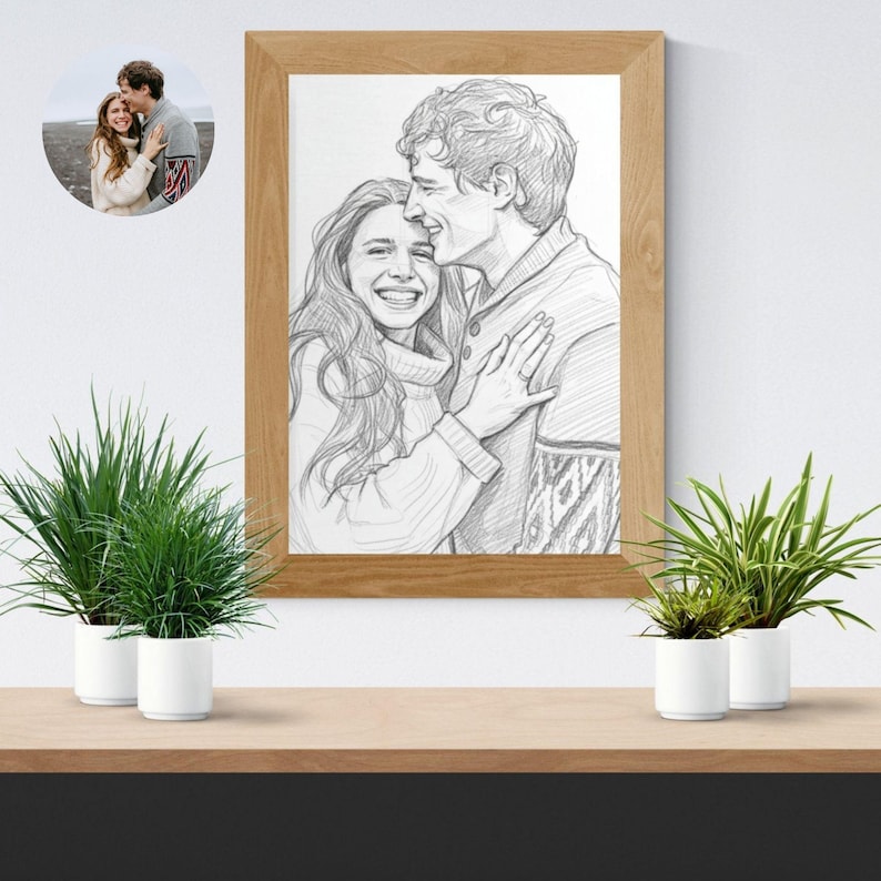 May include: A framed pencil sketch of a couple embracing, with a smaller circular photo in the upper left corner. The sketch is in a wooden frame and features a man and woman in sweaters. Two potted plants sit on a wooden shelf below.
