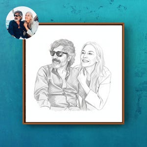 May include: A pencil sketch portrait of a couple, framed in a brown wooden frame. The portrait depicts a man with sunglasses and a woman, both smiling. A smaller, color photo of the couple is in the upper left corner. The background is a teal blue.