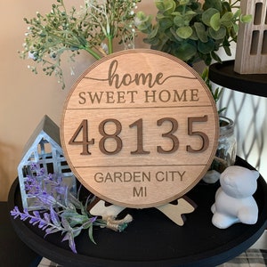 May include: A round wooden sign with the text "home sweet home" and the number "48135" in a cutout style. The sign also includes the text "Garden City MI".