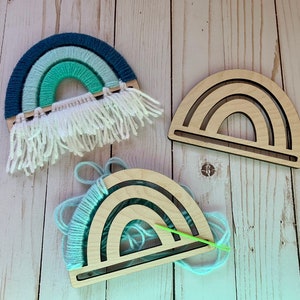 May include: Three wooden rainbow hoops, one with blue, green, and white yarn woven through it, one with yarn being woven through it, and one empty.