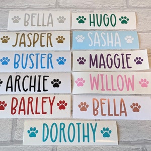 May include: Ten white rectangular stickers with paw prints and dog names printed in various colours. The names are Bella, Jasper, Buster, Archie, Barley, Hugo, Sasha, Maggie, Willow, and Dorothy.