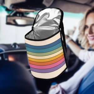 Pode incluir: Uma bolsa de almoço isolada com listras de arco-íris com um zíper preto e alças pretas. A bolsa está aberta e o forro prateado é visível.