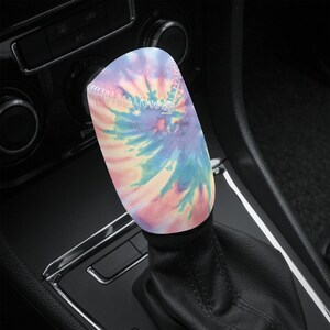 May include: A colourful tie-dye patterned gear shift knob cover. The cover is made of a soft, stretchy material and is designed to fit most standard gear shift knobs.