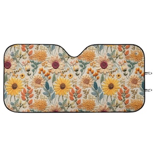 May include: Car sunshade with a floral pattern featuring sunflowers, orange, and yellow flowers, and green leaves. The sunshade has a black border and is designed to fit a car windshield. The design is a repeating pattern of embroidered-style flowers.