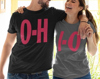 May include: Two t-shirts, one black and one gray, each with a large, magenta "O-H" and "-O" design. The shirts are worn by a smiling couple, suggesting a matching set or a couples' theme.