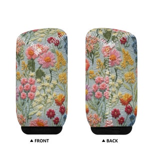 May include: A blue and white can cooler with a floral embroidery pattern. The cooler has a black bottom and a white seam around the top.