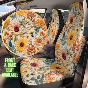 Può includere: Coprisedili per auto con motivo floreale in stile ricamo, caratterizzato da girasoli gialli, fogliame arancione e foglie verde acqua su sfondo crema. Un inserto circolare mostra la texture dettagliata della stampa botanica.