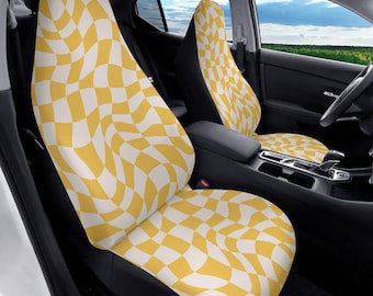 May include: A pair of car seat covers featuring a repeating wavy checkerboard pattern in mustard yellow and white. The fabric covers the entire front and back surfaces of the two front vehicle seats, including the headrests and seat cushions.