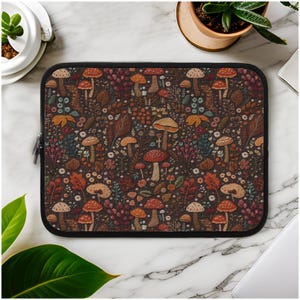 May include: A laptop sleeve featuring a dark brown background with a repeating pattern of colourful mushrooms, leaves and flowers. The sleeve has a black zipper.