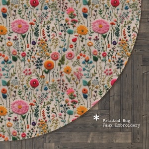Op de afbeelding: Rond tapijt met een bloemenpatroon in tinten roze, oranje, geel, groen en blauw. Het tapijt heeft een nep-borduurwerkontwerp dat eruitziet als gestikte bloemen. De tekst "Printed Rug Faux Embroidery" staat in de rechterbenedenhoek.