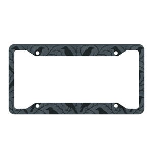 Pode incluir: Uma moldura de placa de carro cinza escuro com um padrão repetido de corvos pretos empoleirados em galhos espinhosos. A moldura tem formato retangular com cantos arredondados e furos pré-perfurados. O design é de tema gótico ou Halloween.