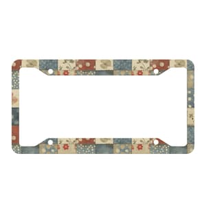May include: License plate frame with a patchwork design. The frame features a repeating pattern of squares in red, blue, and beige, with floral and polka dot accents. The frame has three holes for mounting.