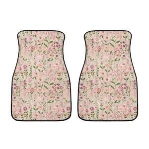 May include: A set of two car floor mats with a floral pattern. The mats are beige with pink and purple flowers and green leaves.