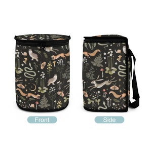 May include: Black insulated lunch bag with a zipper closure. The bag features a repeating pattern of woodland animals, plants, and mushrooms on a dark background.