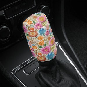 Puede incluir: Una palanca de cambios blanca con un patrón floral colorido. El patrón presenta flores rosas, naranjas, amarillas, azules y verdes.