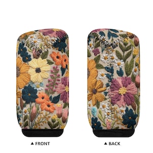 May include: Two floral embroidered shift boot covers. The covers feature a beige background with colorful embroidered flowers in shades of yellow, orange, pink, and blue. The front and back are labeled.