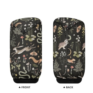 May include: Two black beverage sleeves with a whimsical forest pattern. The design includes a running hare, snake, mushrooms, and moths. The front and back are labeled. The sleeves are made of a soft, flexible material.