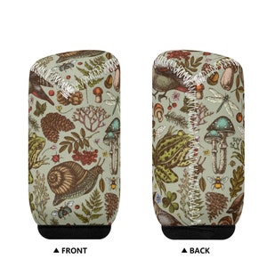 May include: A green can cooler featuring a vintage illustration of mushrooms, frogs, snails, birds, and other woodland creatures. The cooler has a black base and white stitching around the edges.