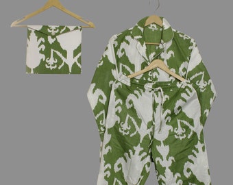 May include: Green and white patterned pajama set, including a long-sleeved top, pants, and a matching pouch. The set is displayed on wooden hangers against a gray background. The pattern features an abstract design.