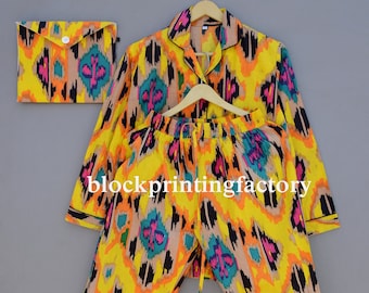 May include: A yellow, orange, pink, black, and teal patterned pajama set with a matching pouch. The set has a button-up top with long sleeves and drawstring pants.