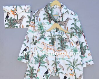 Puede incluir: Pijama blanco con estampado de jungla con cebras, leopardos, tucanes y palmeras. El pijama incluye una camisa de manga larga con cuello abotonado y pantalones a juego.