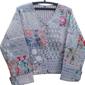 Könnte beinhalten: Eine graue gesteppte Jacke mit Patchwork-Design, das florale und Paisley-Muster in verschiedenen Farben zeigt. Die Jacke hat einen V-Ausschnitt und einen Knopfverschluss.