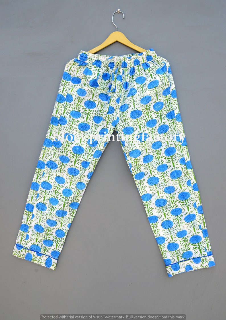 May include: White cotton pants with a blue floral print. The pants have an elastic waistband and a drawstring.