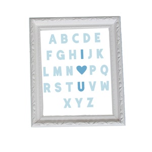 Könnte beinhalten: Ein weiß gerahmtes Bild mit einem blauen und weißen Alphabetdruck. Der Buchstabe "I" ist durch ein blaues Herz ersetzt und der Buchstabe "U" durch ein blaues Herz.