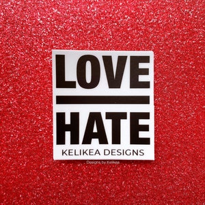 May include: White sticker with black text that reads "LOVE HATE" with the word "LOVE" above a black line and the word "HATE" below the line. The sticker also has the text "Kelikea Designs" and "Designs by Kelikea" in smaller black text.