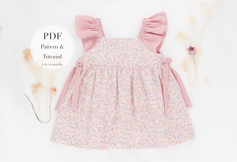 K&ouml;nnte beinhalten: Ein rosa-wei&szlig;es Babykleid mit floralem Muster, gekr&auml;uselten rosa &Auml;rmeln und rosa B&auml;ndern. Das Kleid ist f&uuml;r Babys von 1 bis 24 Monaten. Der Text "PDF Pattern & Tutorial" befindet sich auf einem wei&szlig;en Kreis.