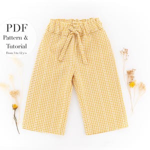 May include: Yellow and white gingham patterned pants with a tie waist. The pants are wide-legged and have a comfortable, casual style. The image also includes text that says "PDF Pattern & Tutorial From 3 to 12 y/o."