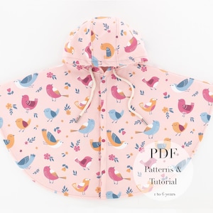 Op de afbeelding: Een roze kinderponcho met een vogel- en bloemenpatroon. De poncho heeft een capuchon en een trekkoord. De afbeelding bevat de tekst "PDF Patterns & Tutorial 1 to 6 years".