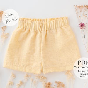 Puede incluir: Un short amarillo con bolsillos laterales. El short tiene una cintura elástica y está hecho de una tela suave y texturizada. El texto "PDF Woman Short Pattern & Tutorial XS to XXL" es visible en la esquina inferior derecha de la imagen.