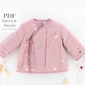 Puede incluir: Una chaqueta de bebé rosa claro con cierre cruzado y patrones geométricos plateados. La chaqueta tiene mangas largas y un cierre de lazo. El texto en la imagen dice "PDF Pattern & Tutorial From 9 to 30 months."