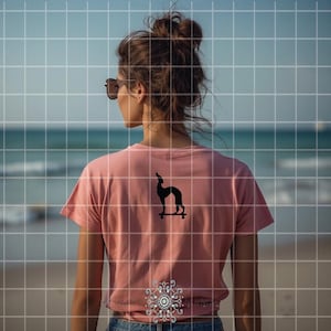May include: A dusty rose t-shirt with a black graphic of a dog on a skateboard. The shirt is short-sleeved and the person is wearing sunglasses. The background is a beach scene with the ocean and sky.