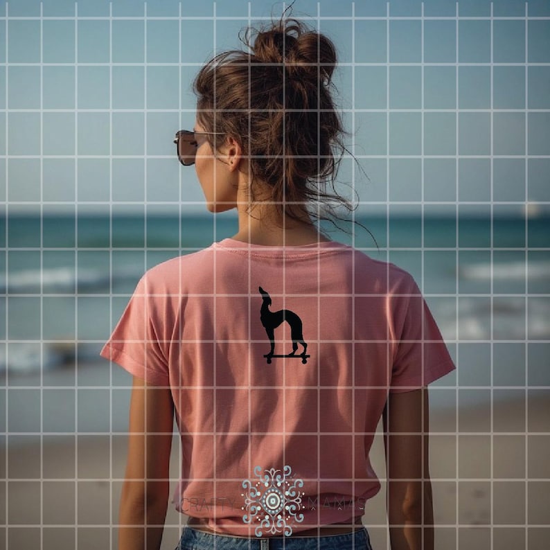 May include: A dusty rose t-shirt with a black graphic of a dog on a skateboard. The shirt is short-sleeved and the person is wearing sunglasses. The background is a beach scene with the ocean and sky.