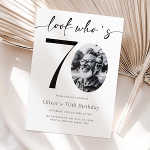 May include: A white birthday invitation with the text "look who's 70" in a script font. The number 70 is large and black. An oval photo of a smiling man is in the center. The invitation includes event details.