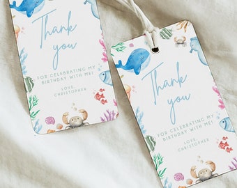 May include: Two blue and white thank you tags with a watercolor ocean theme. The tags feature a whale, fish, coral, and a crab. The text on the tags reads "Thank you" and "For celebrating my birthday with me!"
