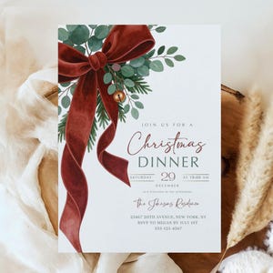Könnte beinhalten: Eine Einladung zum Weihnachtsessen mit einer bordeauxfarbenen Samtschleife und Grün. Die Einladung enthält den Text "Christmas Dinner" und Veranstaltungsdetails. Eine goldene Glocke und ein neutraler Hintergrund vervollständigen das Design.