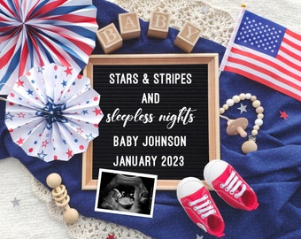 May include: A letter board with the text "Stars & Stripes and sleepless nights Baby Johnson January 2023".  The board is surrounded by red, white, and blue decorations, including a baby's ultrasound image, a small American flag, and a rattle.