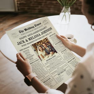 May include: A vintage newspaper style print with a photo of a couple in a restaurant. The headline reads "Happy 50th Anniversary! Jack & Melissa Johnson Were Married on February 28th, 1975".