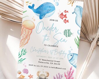 Könnte beinhalten: Eine blaue und weiße Einladungskarte mit dem Text "Join Us Oneder the Sea to Celebrate Christopher's 1st Birthday" und Details zur Party. Die Karte zeigt Aquarell-Illustrationen von Meeresbewohnern, darunter ein Wal, ein Seepferdchen, eine Qualle und Fische.
