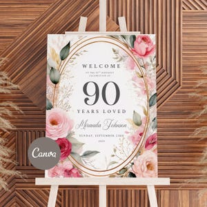 May include: A welcome sign for a 90th birthday celebration. The sign features an oval gold frame with pink and red floral accents. The text reads "WELCOME TO THE 90TH BIRTHDAY CELEBRATION OF 90 YEARS LOVED Miranda Johnson SUNDAY, SEPTEMBER 23RD 2025".