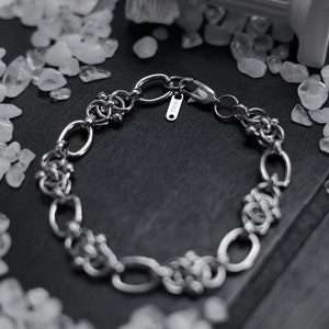 May include: A silver chain bracelet with a clasp and a small tag that says "ISURI".
