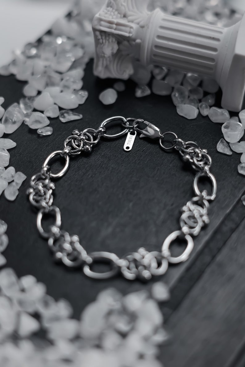 May include: A silver chain bracelet with a clasp and a small tag that says "ISURI".