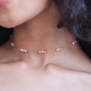 Puede incluir: Un delicado collar choker de cadena dorada con cuentas iridiscentes. El collar es simple y elegante, perfecto para el uso diario.