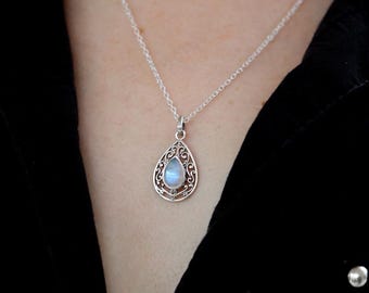May include: Silver pendant necklace featuring a teardrop-shaped moonstone. The moonstone is set within an ornate, openwork silver frame. The necklace hangs on a delicate silver chain, creating an elegant and timeless piece of jewelry.