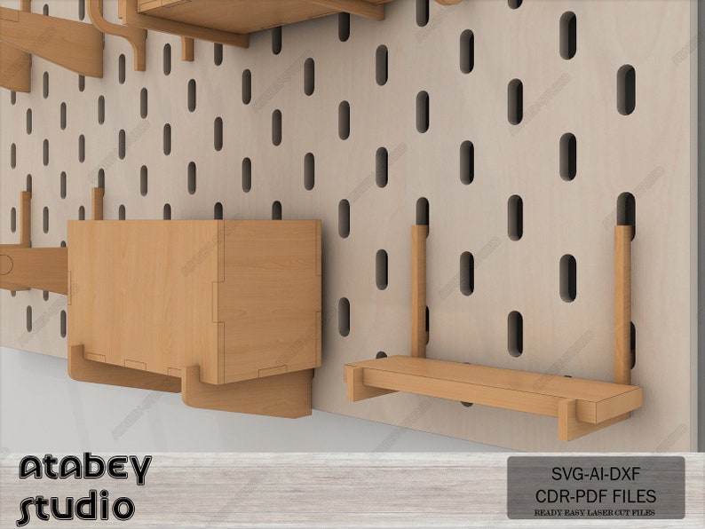 May include: A set of wooden shelves and storage boxes designed for a pegboard wall. The shelves are made of light brown wood and have a simple, modern design. The storage boxes are also made of light brown wood and have a rectangular shape. The pegboard wall is made of a light beige material and has a grid pattern of holes. The image includes the text "Atabey studio" and "SVG-AI-DXF CDR-PDF FILES READY EASY LASER CUT FILES".