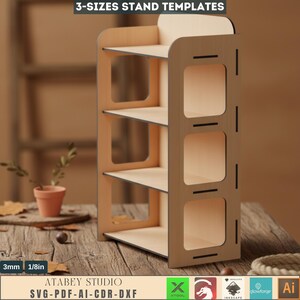 May include: A wooden, three-tiered stand with a light-colored finish. The stand has a rectangular shape with rounded edges and square cutouts on the side. The text "3-SIZES STAND TEMPLATES" is at the top. The stand is 1/8in thick.