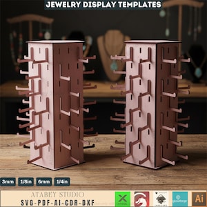 May include: Two wooden jewelry display stands with multiple hooks for hanging necklaces and bracelets. The stands are light brown with a square shape and are labeled with the text "JEWELRY DISPLAY TEMPLATES" and "ATABEY STUDIO".